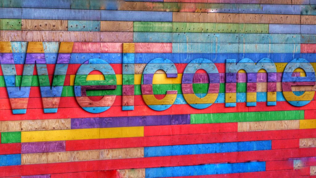 welcome banner made of wood and painted in rainbow colours