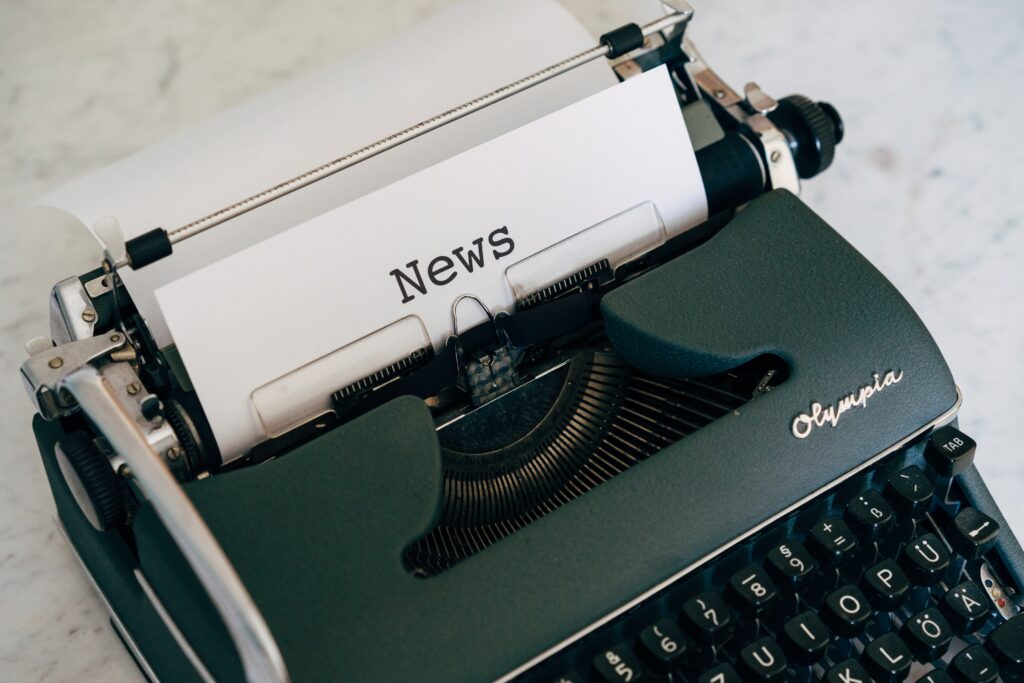 a typewriter with a piece of paper in it and someone has typed the word "NEWS"