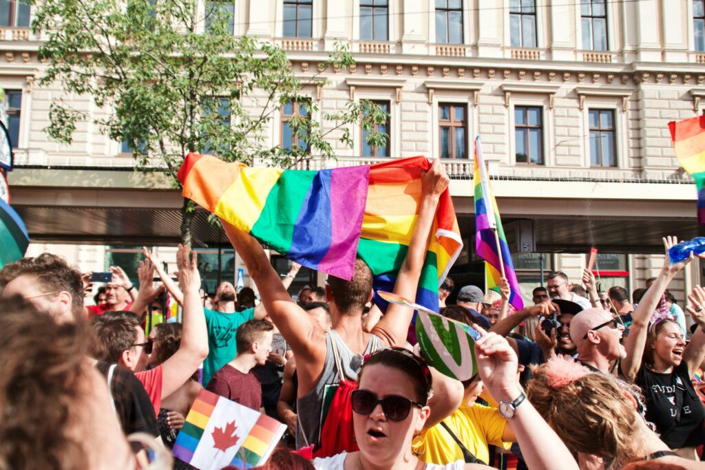 a crowd of people on a city street raising pride flags